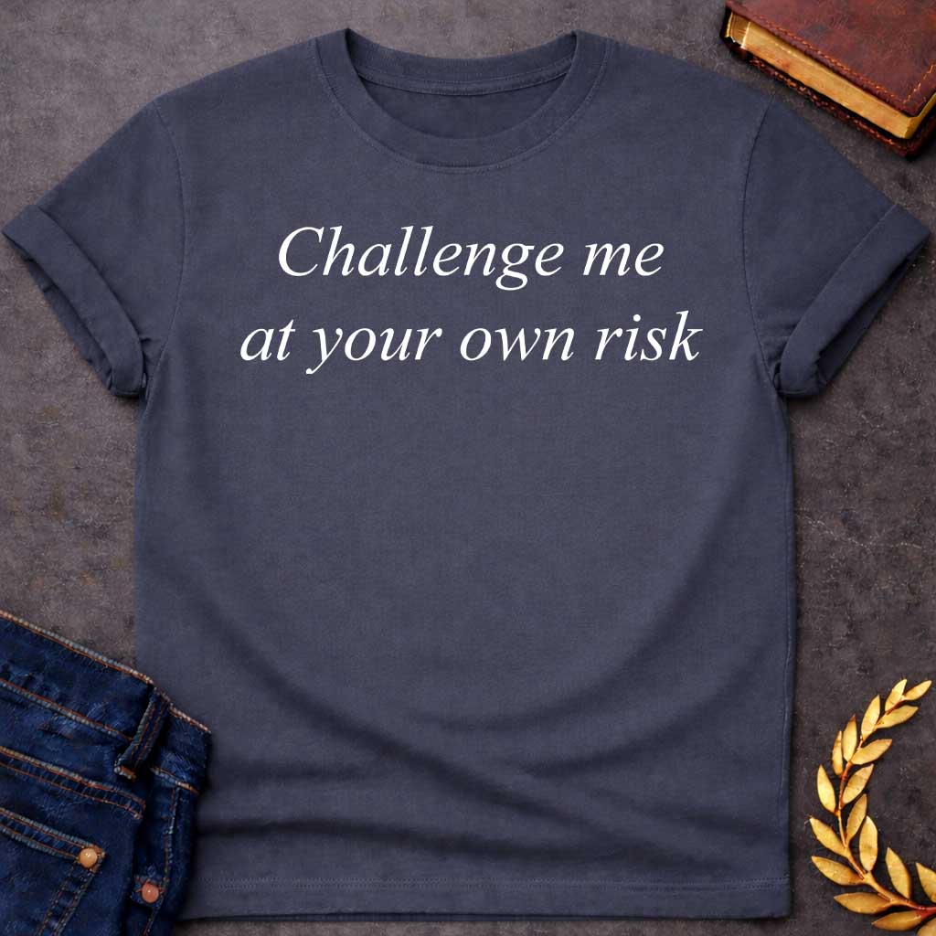 Dark Heather T-shirt graphic in white featuring large elegant italic serif text reading "Challenge me at your own risk" — a bold warning referencing Athena, the Greek Goddess of Wisdom and War Strategy