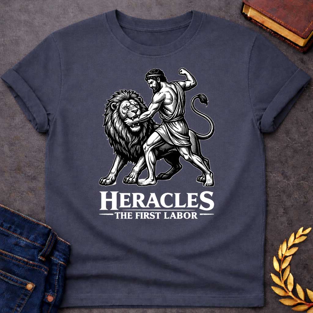 Dark Heather T-shirt. The illustration features a woodcut-style depiction of the Greek hero Heracles wrestling the Nemean lion. Below the artwork, the text reads in white "HERACLES" in a large, distressed serif font, followed by the smaller subtitle "THE FIRST LABOR,"