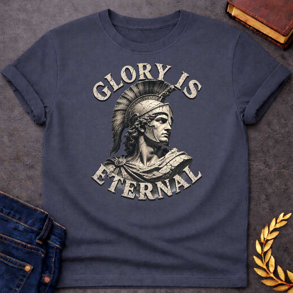 Dark Heather T-Shirt with a classical illustration of a Greek warrior in profile, rendered in sepia tones with weathered, cracked texture. The figure wears an ornate Corinthian helmet with black horsehair crest, long curly hair, and armor with a draped cloak. The warrior gazes stoically with classical features. Distressed serif letters spell 'GLORY IS' above and 'ETERNAL' below. The design has a vintage, monumental quality reminiscent of ancient statuary, emphasizing themes of heroism, honor, and timeless l