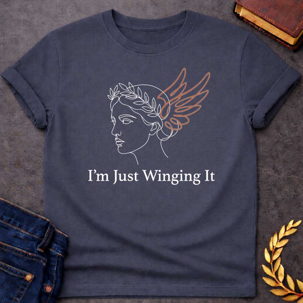 Dark Heather T-shirt with a Minimalist line art illustration of a classical Greek profile with a laurel wreath crown and large terracotta-colored wings extending from the head. Elegant continuous line drawing style. Text reads 'I'm Just Winging It' in serif font below. References Nike, the goddess of victory, with a humorous modern spin. Blends classical mythology with relatable contemporary humor about improvisation and navigating life without a plan.