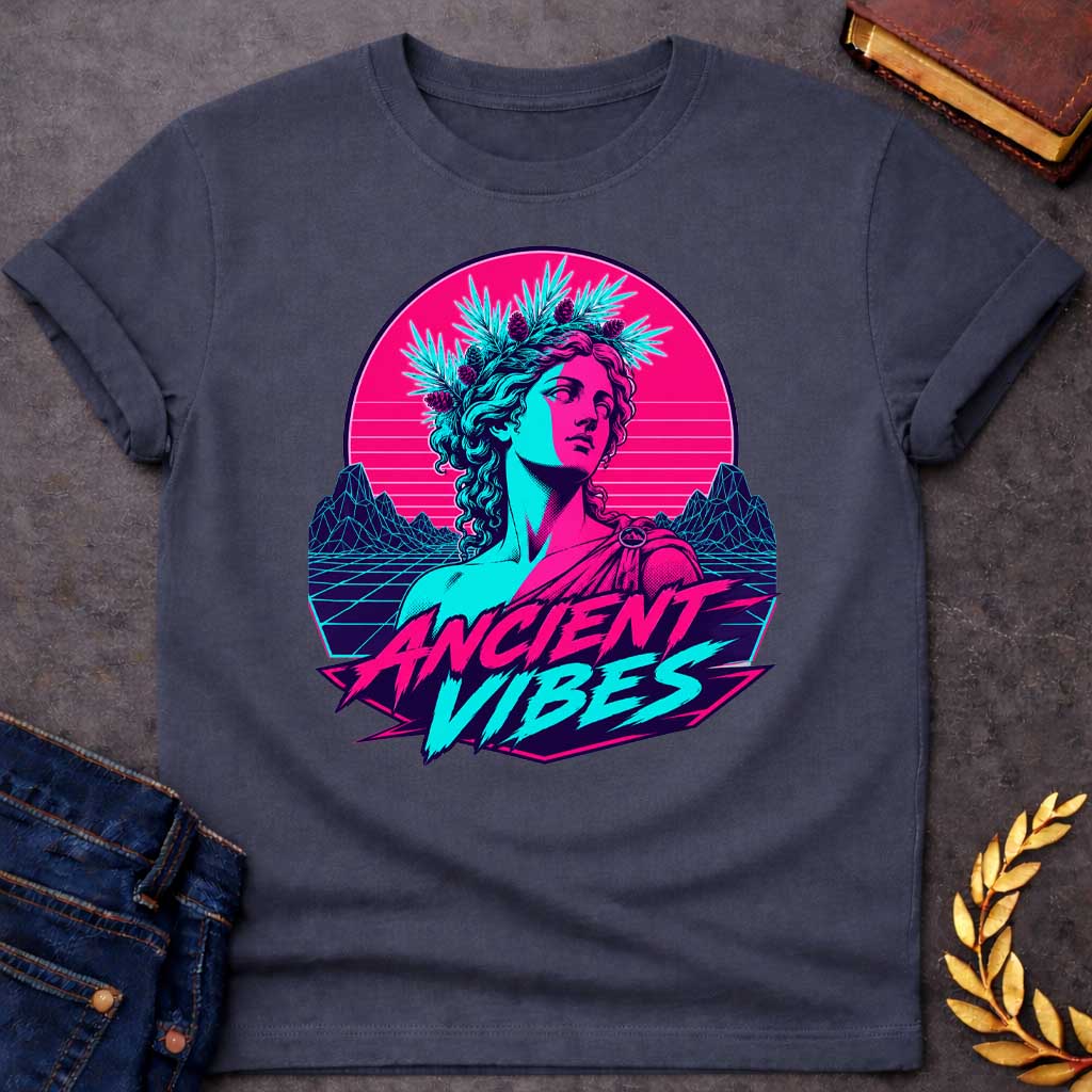 Dark Heather T-shirt with a Vaporwave-style illustration of a classical Greek Nymph bust in neon magenta and cyan. The figure wears a laurel wreath crown and draped robes with split-color digital aesthetic. Geometric mountains and grid pattern landscape create a retro 80s vibe. Horizontal scan lines suggest digital distortion. Bold text reads 'ANCIENT VIBES' in magenta and cyan with star accents. Navy blue border frames the design. Blends classical Greek aesthetics with modern synthwave style.
