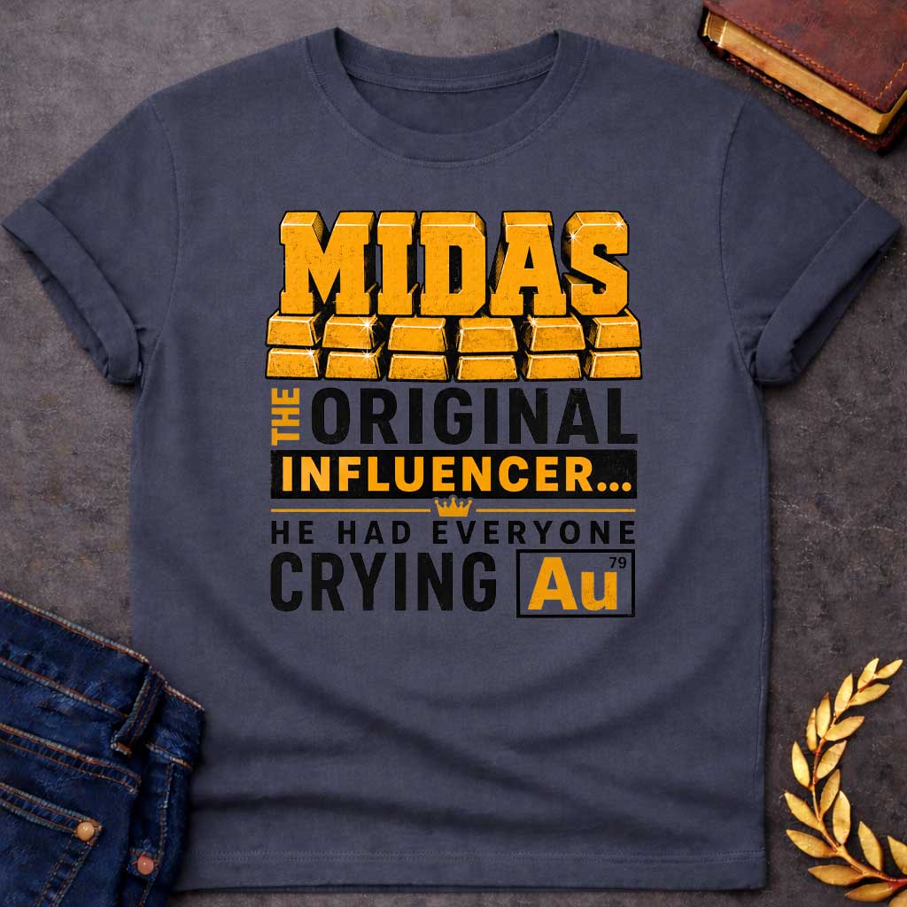 Dark Heather t-shirt with A Bold typographic Greek mythology design featuring stacked gold bar lettering spelling "MIDAS" above the phrase "The Original Influencer... He Had Everyone Crying Au." The design uses distressed black and metallic gold typography with a small crown icon and a gold-themed chemical element "Au" symbol, creating a humorous King Midas pun in a vintage-inspired graphic style.
