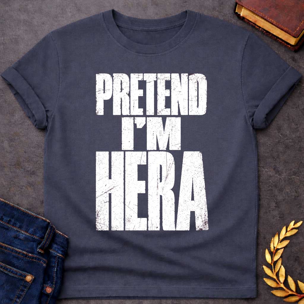 Dark Heather t-shirt with a Pretend I’m Hera Greek mythology design featuring bold distressed white typography on a transparent background. The stacked text reads “PRETEND I’M HERA” in a rugged vintage block font, creating a humorous design inspired by Hera, the Greek goddess of marriage, women, family, and queen of the Olympian gods.