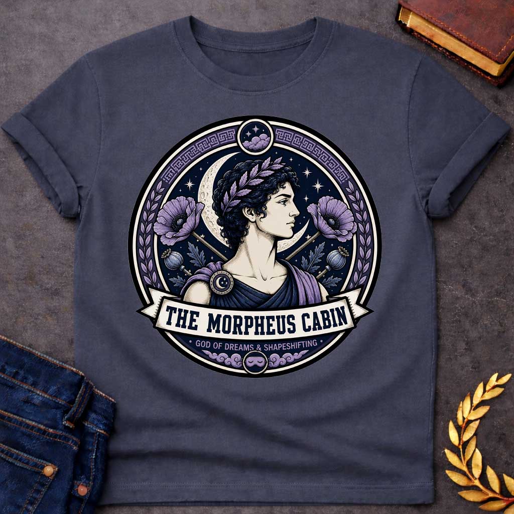 Dark Heather t-shirt with a Morpheus Greek mythology cabin design featuring the god of dreams and shapeshifting in a navy and lavender circular emblem. Morpheus wears a laurel crown and classical robes, surrounded by a crescent moon, stars, purple poppies, poppy pods, clouds, and Greek key details. Text reads “The Morpheus Cabin” and “God of Dreams & Shapeshifting,”