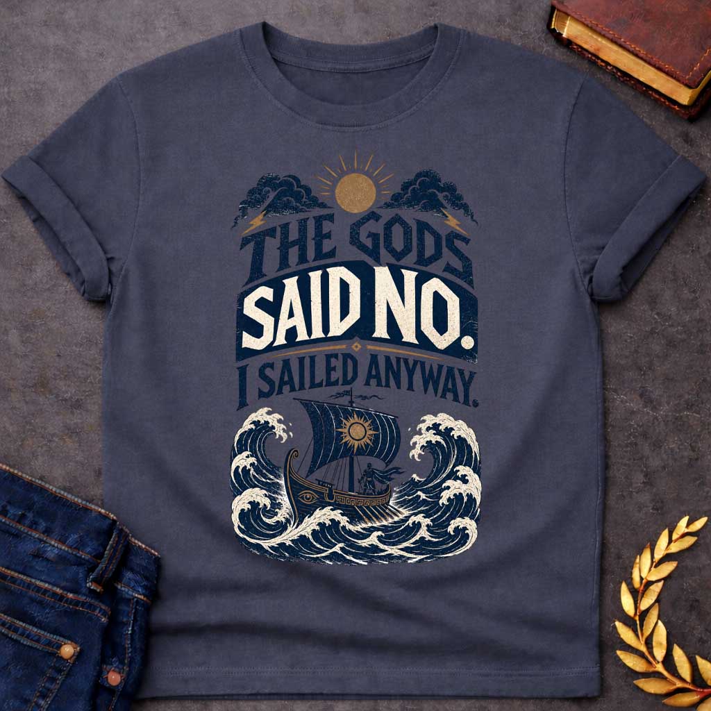 Dark Heather t-shirt with a Vintage Greek mythology design featuring the bold phrase “The Gods Said No. I Sailed Anyway.” An ancient Greek ship battles towering ocean waves beneath storm clouds, lightning bolts, and a glowing sun. Distressed navy, cream, and gold artwork captures the defiant spirit of Odysseus and The Odyssey.
