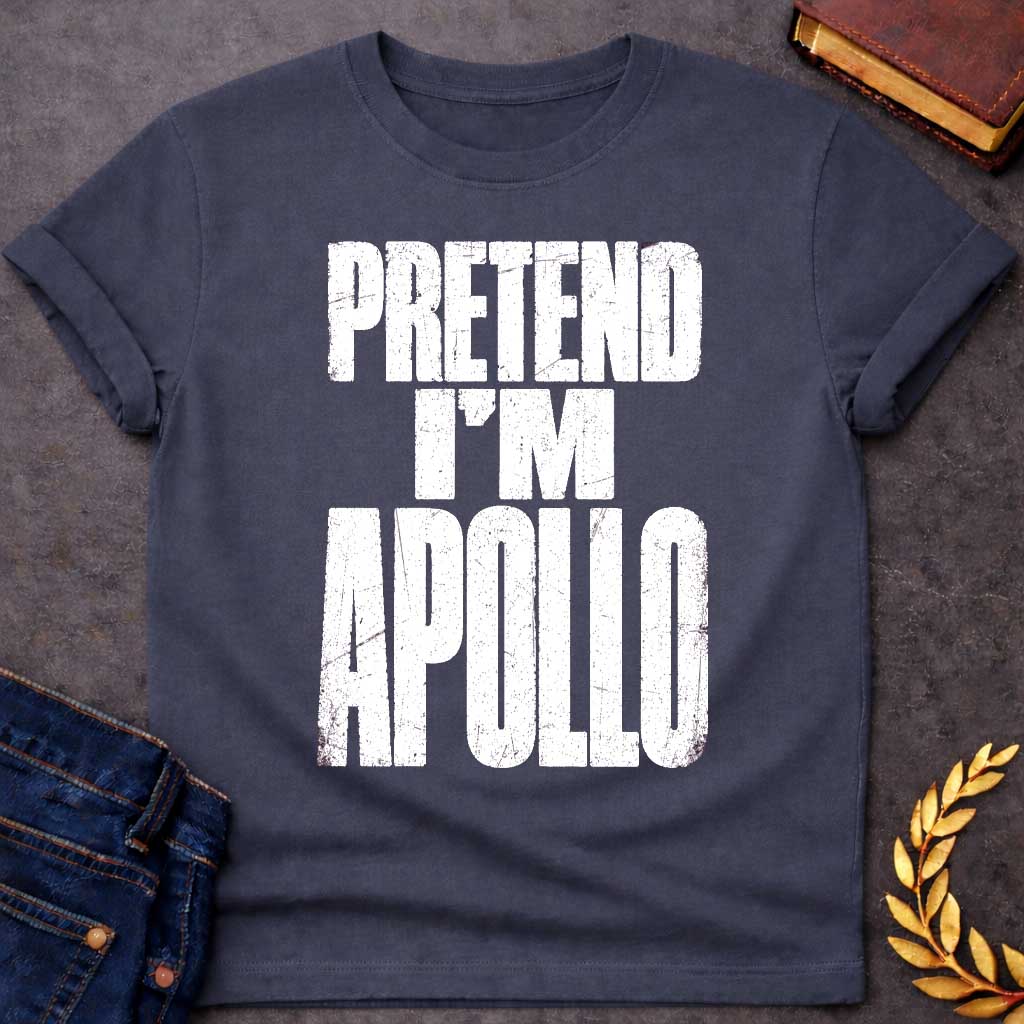 Dark Heather t-shirt with a Pretend I’m Apollo Greek mythology design featuring bold distressed white typography on a transparent background. The stacked text reads “PRETEND I’M APOLLO” in a rugged vintage block font, creating a simple humorous design inspired by Apollo, the Greek god of the sun, music, poetry, prophecy, and healing.