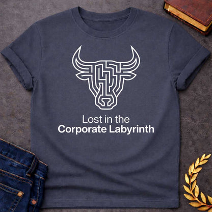 Dark Heather T-shirt with a Minimalist line art illustration of a Minotaur head rendered entirely as a complex maze pattern in navy blue and white. The bull's horns and facial features form pathways and corridors. Text reads 'Lost in the Corporate Labyrinth' below. Clever wordplay merges Greek mythology with modern commentary on workplace frustration, bureaucratic confusion, and corporate system entrapment.