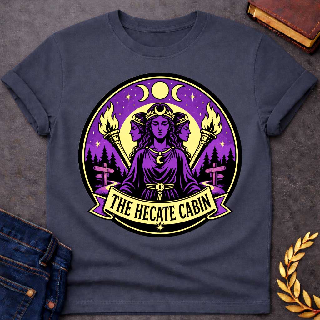 Dark Heather t-shirt with a Hecate Greek mythology design featuring the triple goddess with three faces, crescent moon symbols, glowing torches, stars, and a mystical purple night sky. Forest silhouettes and crossroads signs represent Hecate’s connection to magic and crossroads, framed in a circular camp-style emblem with the text “The Hecate Cabin.”
