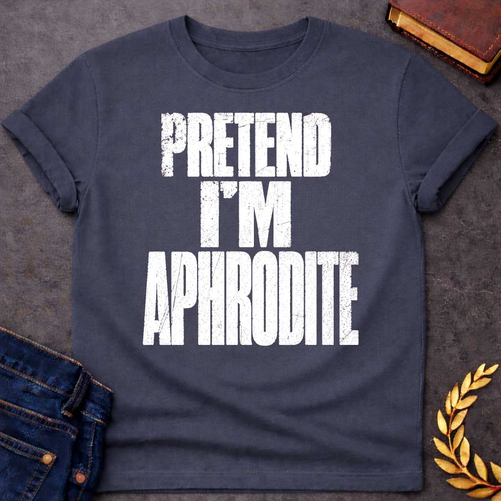 Dark Heather t-shirt with a Pretend I’m Aphrodite Greek mythology design featuring bold distressed white typography on a transparent background. The stacked text reads “PRETEND I’M APHRODITE” in a rugged vintage block font, creating a simple humorous design inspired by Aphrodite, the Greek goddess of love and beauty.