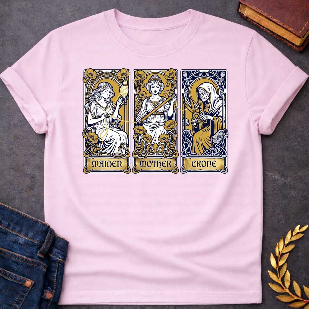 Light Pink T-shirt graphic featuring three Art Nouveau-style tarot card panels in navy, gold, and white, each depicting one of the Moirai, the Greek Fates, as the triple goddess archetypes. The first panel shows the Maiden as a young woman spinning a golden thread from a spindle amid poppies, labelled "Maiden." The middle panel shows the Mother as a composed woman measuring the thread with a ruler surrounded by blooming poppies, labelled "Mother." The third panel shows the Crone as an elderly hooded woman h