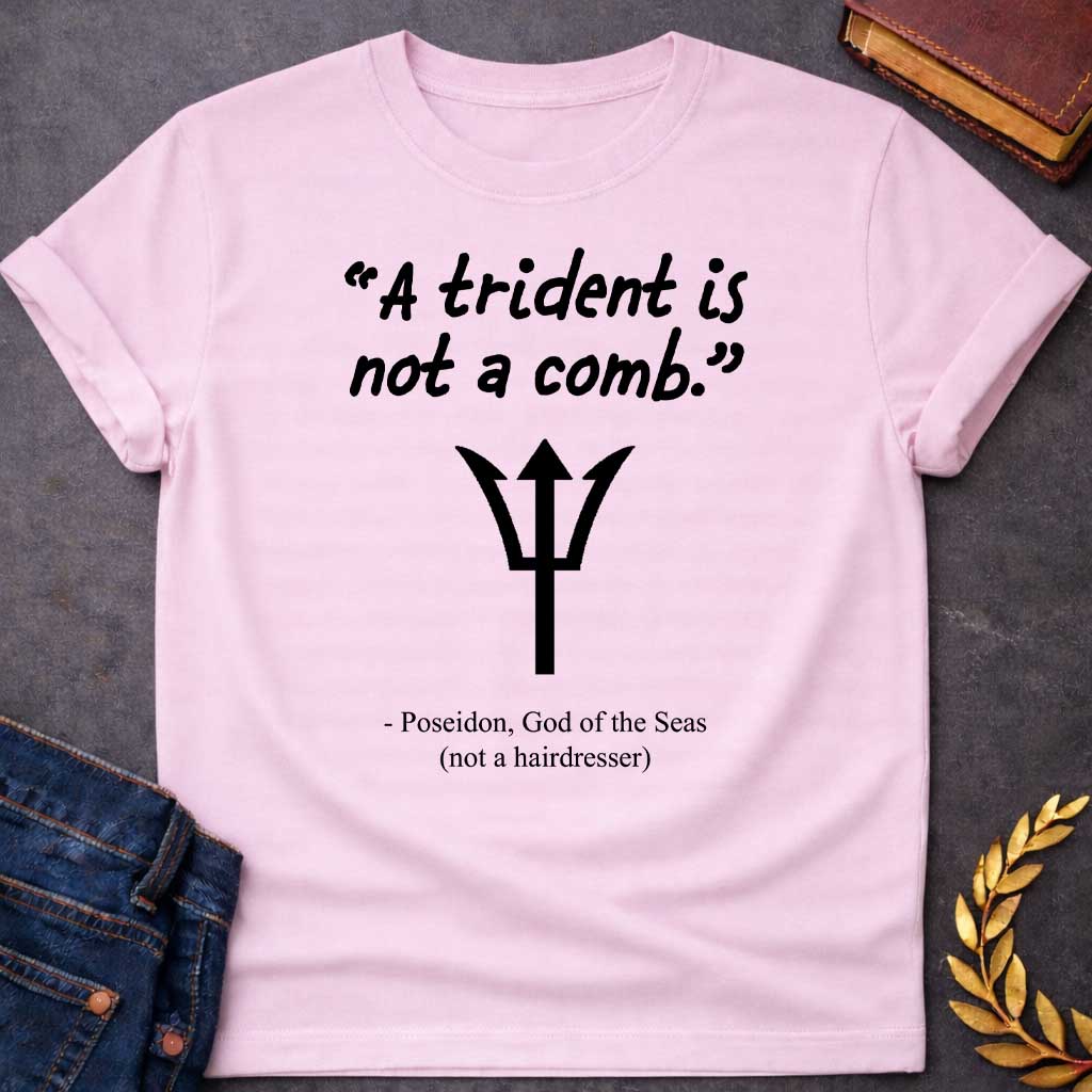 Light Pink T-shirt graphic featuring a black handwritten-style quote reading "A trident is not a comb." above a flat black trident symbol, with the humorous attribution below in clean serif text reading "- Poseidon, God of the Seas (not a hairdresser)