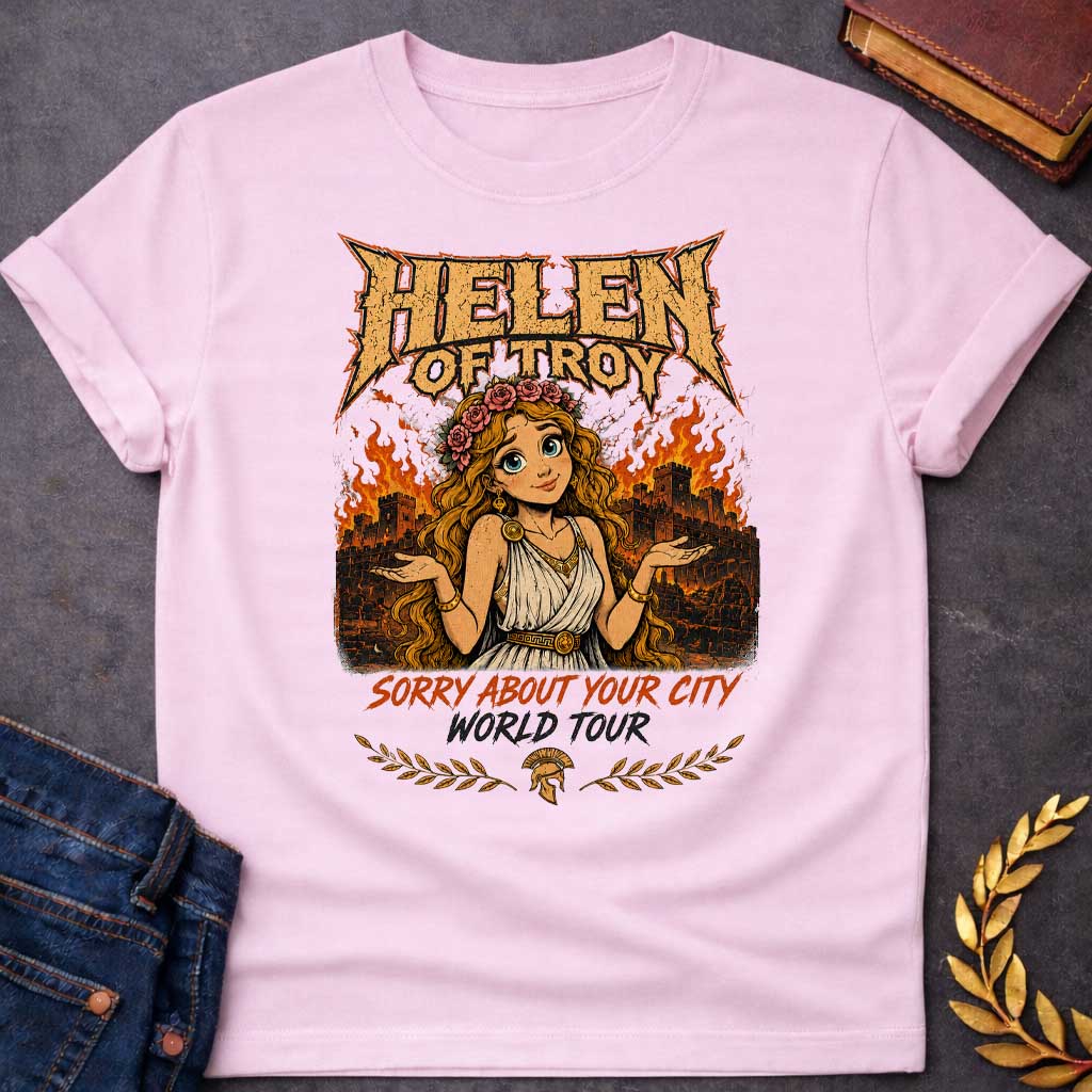 Light Pink T-shirt with a heavy metal style graphic featuring a cartoon Helen of Troy with big blue eyes and a flower crown. She shrugs playfully while standing in front of a burning ancient city wall. At the top, "HELEN OF TROY" is written in a jagged, metallic font. Below her, the text reads "SORRY ABOUT YOUR CITY" in orange and "WORLD TOUR" in black brush script, accented by a Spartan helmet and laurel leaves.