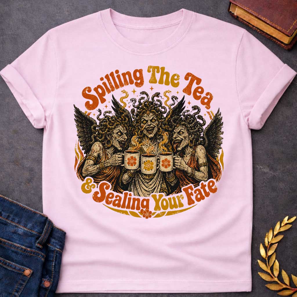 Light Pink T-shirt with a Humorous illustration blending modern gossip culture with Greek mythology. Three Furies with serpent hair and black wings wear classical robes, each holding a decorative tea cup with floral designs. Their expressions are menacing yet mischievous. Text reads 'Spilling The Tea & Sealing Your Fate.' Black, cream, orange, and gold color scheme with decorative flourishes. Playfully references both tea-spilling gossip and divine vengeance and fate.