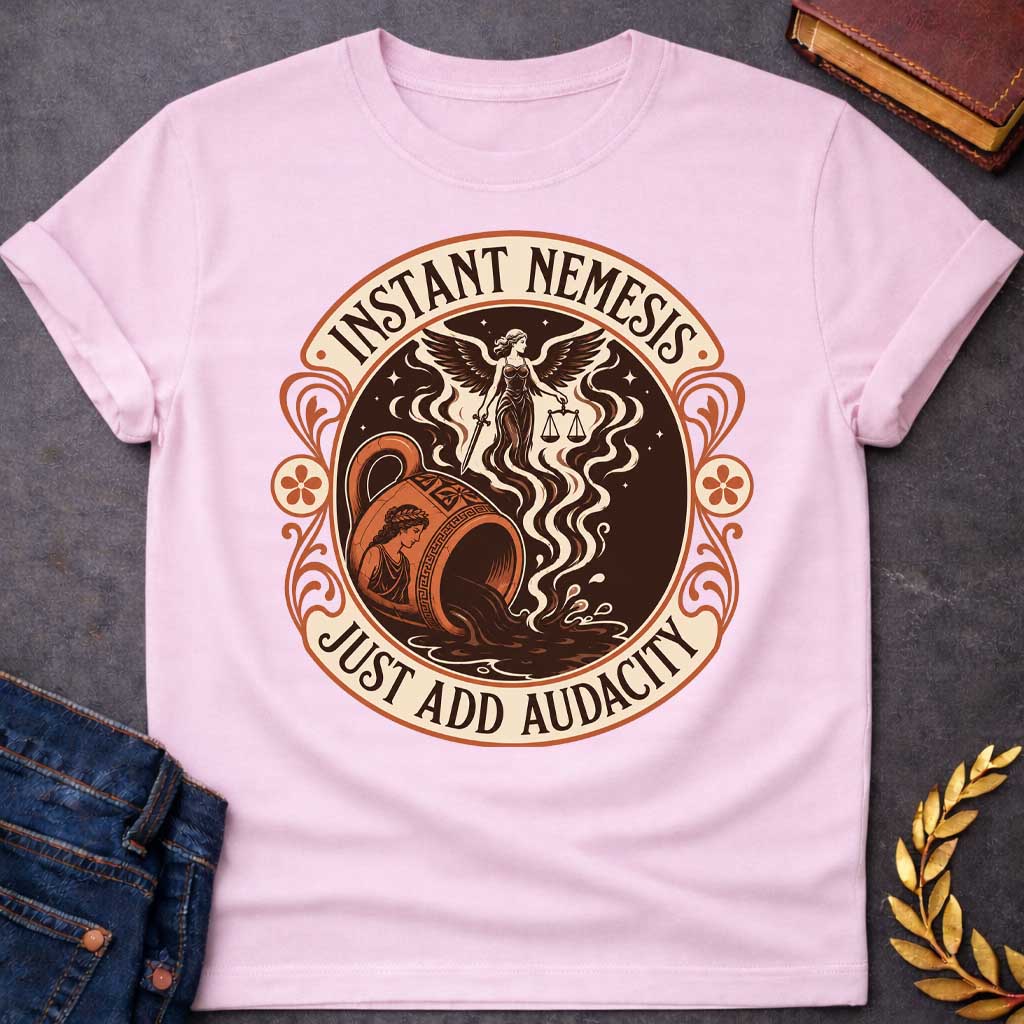Light Pink T-shirt with a Vintage product-label style circular design in terracotta, cream, and dark brown. Text reads 'INSTANT NEMESIS' at top and 'JUST ADD AUDACITY' at bottom. Center features Nemesis, the winged Greek goddess of retribution, holding scales of justice above a spilling Greek vase with a classical Greek warrior profile. Swirling smoke rises from the vessel. Ornate Art Nouveau flourishes and floral medallions frame the design. Humorous take on Greek mythology and divine consequences.