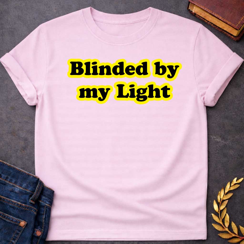 Light Pink T-shirt Streetwear graphic design featuring the phrase "Blinded by my Light" in bold black bubble typography with a vibrant yellow glow. Retro-style aesthetic inspired by Greek mythology and Apollo, the god of light
