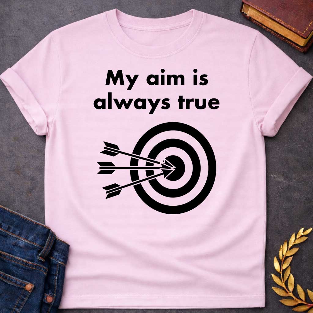 Light Pink T-shirt graphic At the top, the phrase "My aim is always true" is written in a bold, black, sans-serif font across two lines. Below the text is a black and white bullseye target icon. Three black arrows are shown striking the center of the target simultaneously from the left, with their points clustered directly in the "dead center" inner circle