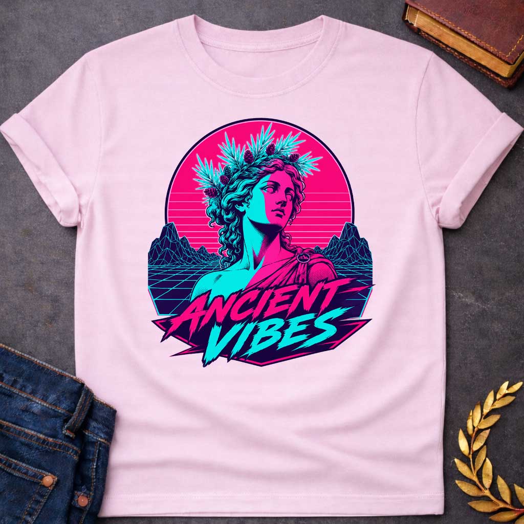 Light Pink T-shirt with a Vaporwave-style illustration of a classical Greek Nymph bust in neon magenta and cyan. The figure wears a laurel wreath crown and draped robes with split-color digital aesthetic. Geometric mountains and grid pattern landscape create a retro 80s vibe. Horizontal scan lines suggest digital distortion. Bold text reads 'ANCIENT VIBES' in magenta and cyan with star accents. Navy blue border frames the design. Blends classical Greek aesthetics with modern synthwave style.
