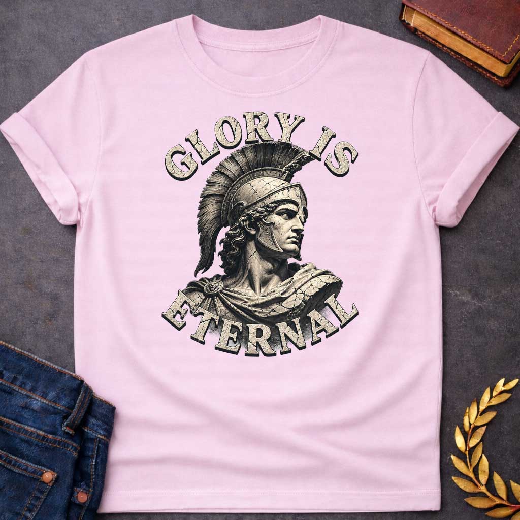 Light Pink T-Shirt with a classical illustration of a Greek warrior in profile, rendered in sepia tones with weathered, cracked texture. The figure wears an ornate Corinthian helmet with black horsehair crest, long curly hair, and armor with a draped cloak. The warrior gazes stoically with classical features. Distressed serif letters spell 'GLORY IS' above and 'ETERNAL' below. The design has a vintage, monumental quality reminiscent of ancient statuary, emphasizing themes of heroism, honor, and timeless leg