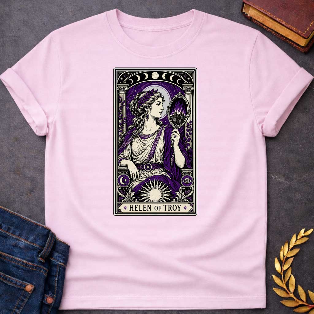 Light Pink T-shirt with an intricate tarot card style graphic featuring Helen of Troy in a Dark Academia aesthetic. She wears a laurel wreath, Greek tunic, and purple robe, holding a hand mirror that reflects a burning city in purple flames. The design has a black, cream, and deep purple color scheme with mystical elements like moon phases, a radiant sun, and an eye symbol. A banner at the bottom reads "HELEN OF TROY" between two stars