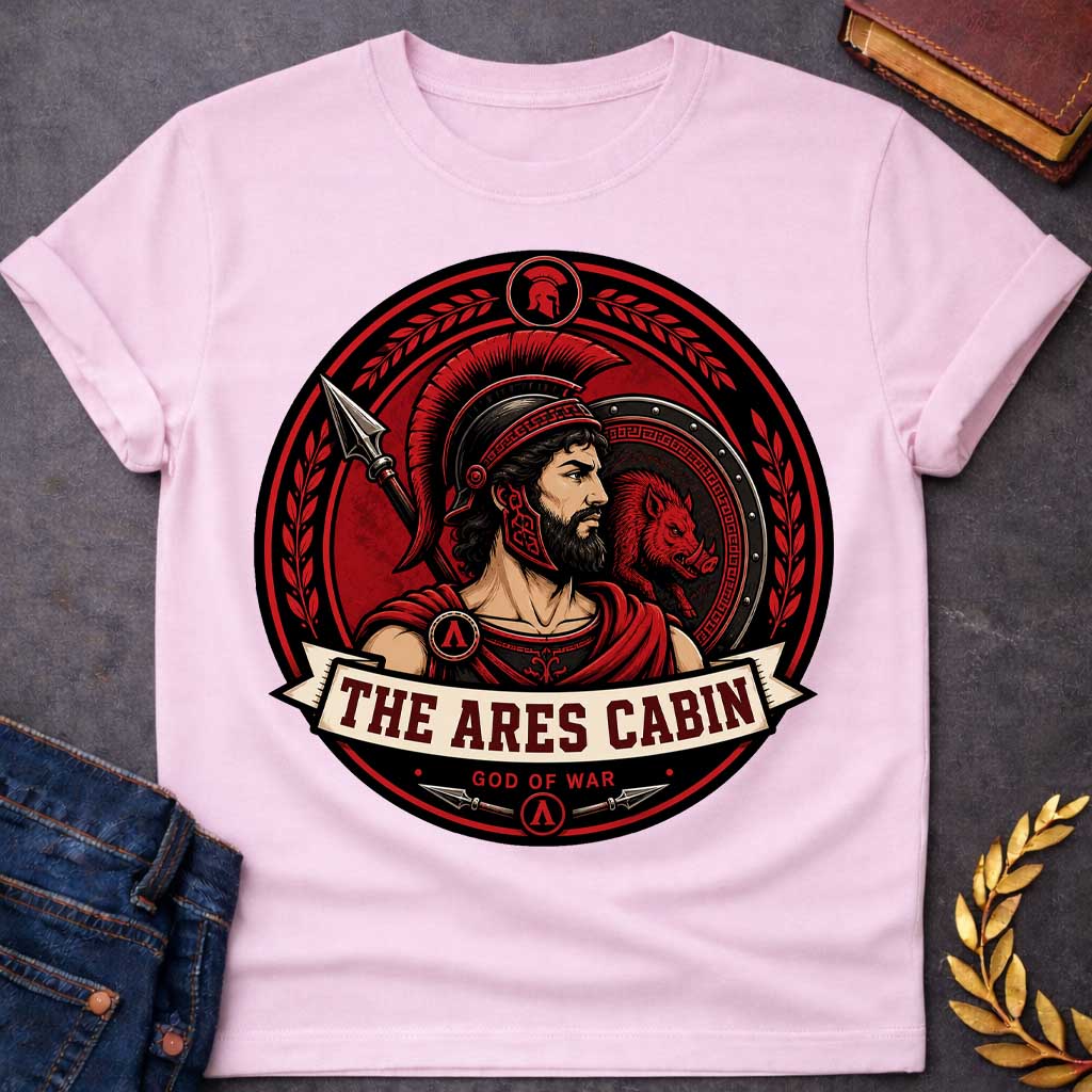 Light Pink t-shirt with a Ares Greek mythology cabin design featuring the god of war in a Spartan-style helmet and armor, framed by a spear, shield with a fierce boar, and laurel branches. Bold red, black, and cream circular camp-style emblem includes the text “The Ares Cabin” and “God of War,”