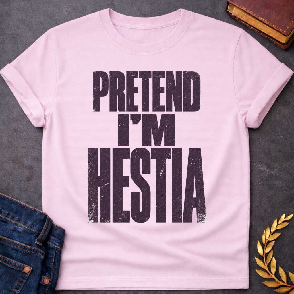 Light Pink t-shirt with a Pretend I’m Hestia Greek mythology design featuring bold distressed dark purple typography on a transparent background. The stacked text reads “PRETEND I’M HESTIA” in a rugged vintage block font, creating a humorous design inspired by Hestia, the Greek goddess of the hearth, home, family, and domestic life.