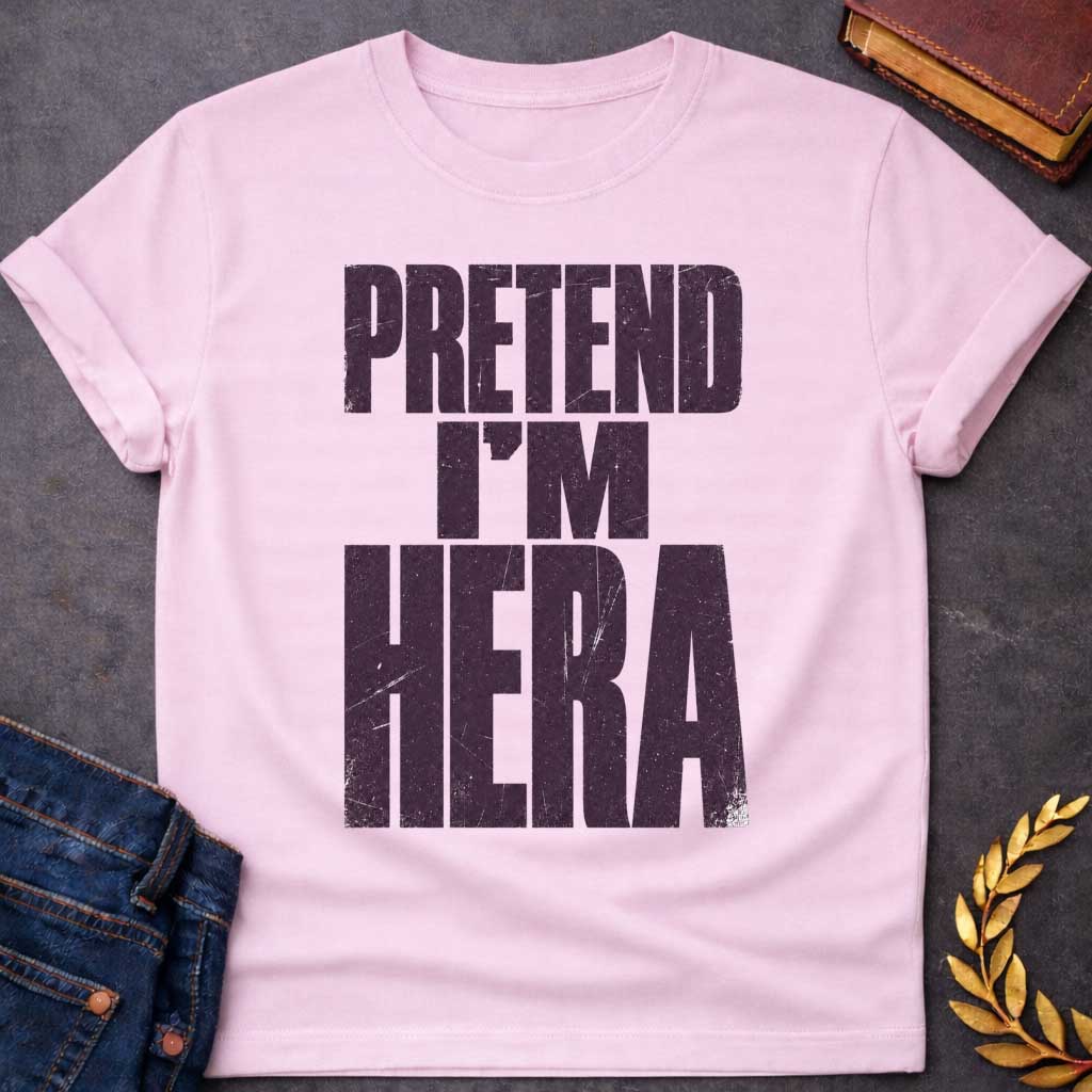 Light Pink t-shirt with a Pretend I’m Hera Greek mythology design featuring bold distressed dark purple typography on a transparent background. The stacked text reads “PRETEND I’M HERA” in a rugged vintage block font, creating a humorous design inspired by Hera, the Greek goddess of marriage, women, family, and queen of the Olympian gods.