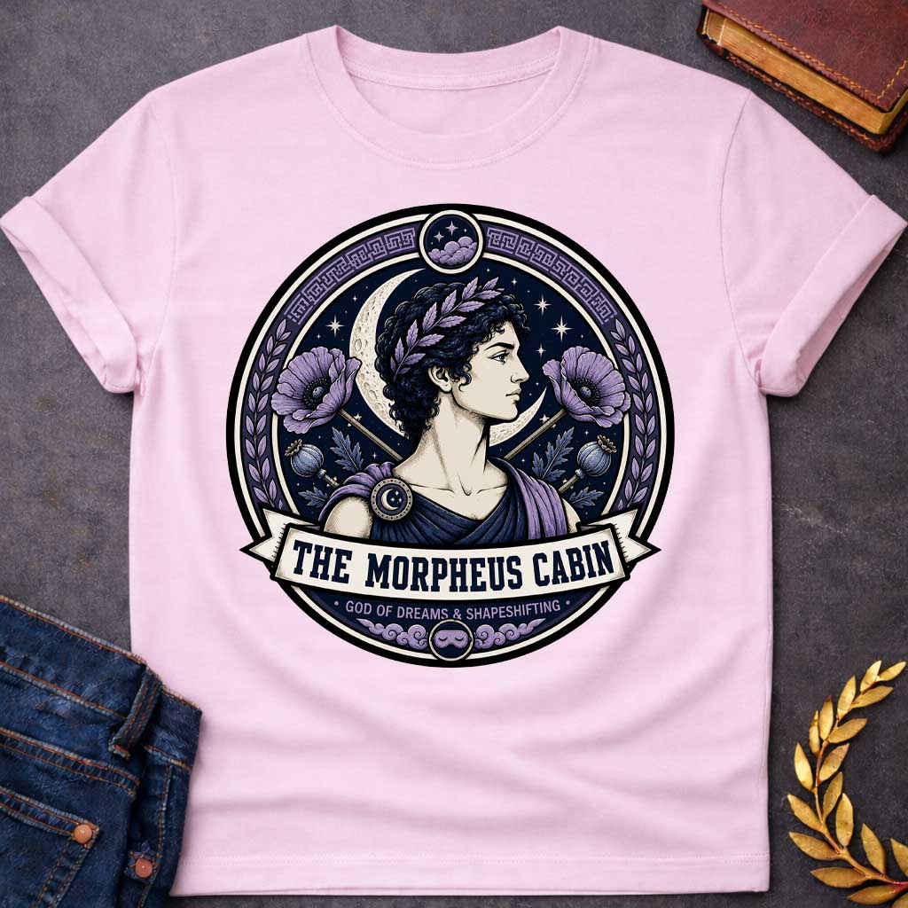 Light Pink t-shirt with a Morpheus Greek mythology cabin design featuring the god of dreams and shapeshifting in a navy and lavender circular emblem. Morpheus wears a laurel crown and classical robes, surrounded by a crescent moon, stars, purple poppies, poppy pods, clouds, and Greek key details. Text reads “The Morpheus Cabin” and “God of Dreams & Shapeshifting,”