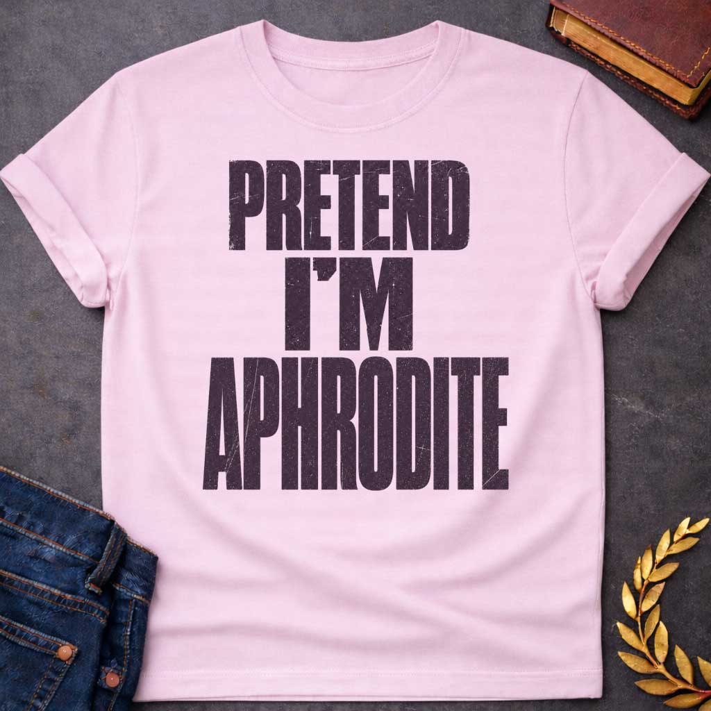 Light Pink t-shirt with a Pretend I’m Aphrodite Greek mythology design featuring bold distressed purple typography on a transparent background. The stacked text reads “PRETEND I’M APHRODITE” in a rugged vintage block font, creating a simple humorous design inspired by Aphrodite, the Greek goddess of love and beauty.