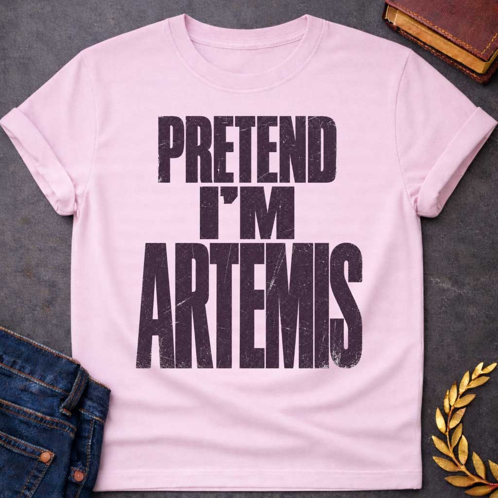 Light Pink t-shirt with a Pretend I’m Artemis Greek mythology design featuring bold distressed purple typography on a transparent background. The stacked text reads “PRETEND I’M ARTEMIS” in a rugged vintage block font, creating a humorous design inspired by Artemis, the Greek goddess of the hunt, wilderness, wild animals, archery, and the moon.