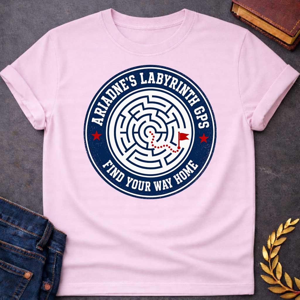 Light Pink T-shirt with A Circular emblem with concentric maze in navy and white, featuring a red dotted path through the labyrinth toward a flag marker. Red stars accent the design. Text reads 'Ariadne's Labyrinth GPS' around the border and 'Find Your Way Home' below. Merges Greek mythology with modern GPS technology, presenting the legendary thread as contemporary guidance. Celebrates finding home through challenging mazes.
