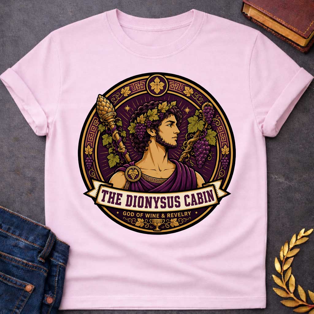 Light Pink t-shirt with a Dionysus Greek mythology cabin design featuring the god of wine and revelry wearing a grapevine crown and purple robes, surrounded by clusters of grapes, vine leaves, a thyrsus, Greek key patterns, and a wine cup. Purple and gold circular emblem includes the text “The Dionysus Cabin” and “God of Wine & Revelry,”