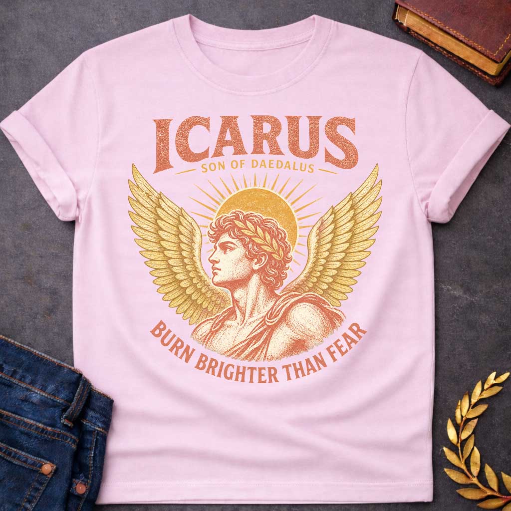 Light Pink t-shirt with a Vintage Icarus Greek mythology design featuring the son of Daedalus in profile with large golden wings, a laurel crown, and a radiant sun behind him. Distressed coral and gold artwork gives the design an antique classical look, with bold text reading “Icarus Son of Daedalus” and “Burn Brighter Than Fear.”