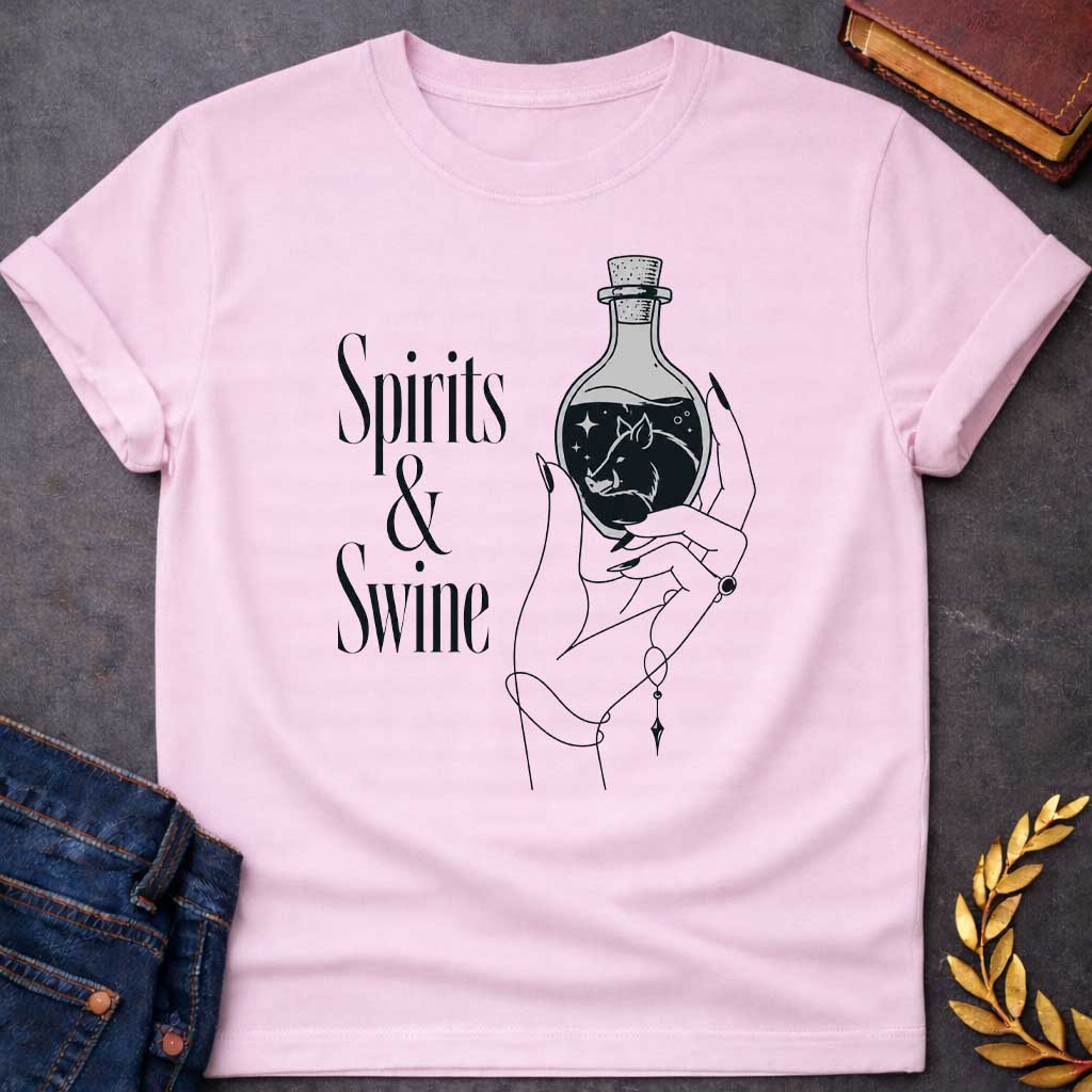 Light Pink T-shirt with a Minimalist line art illustration of a mystical hand holding a potion bottle labeled 'Spirits & Swine.' Inside the dark bottle, a pig silhouette appears amid glowing stars and magical elements. The elegant hand wears decorative bracelets and rings. Black and white aesthetic with witchy, occult vibes. References Circe's legendary enchanted spirits that transformed men into swine. Celebrates ancient magic, potion-making, and mythological transformation with modern witchcraft themes.