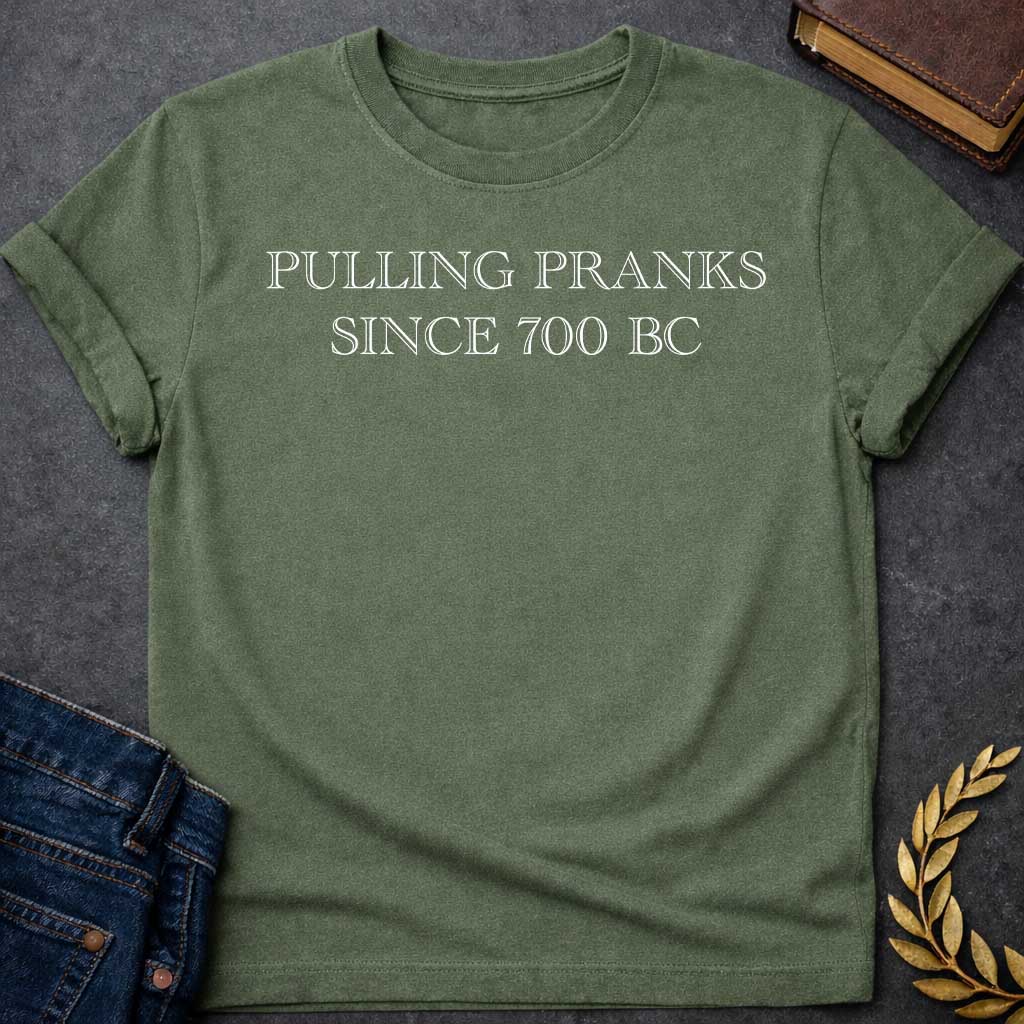 Military Green T-shirt graphic in white text featuring large outlined engraved-style serif text reading "Pulling Pranks Since 700 BC" — a humorous nod to Hermes, the Greek Messenger God and notorious trickster