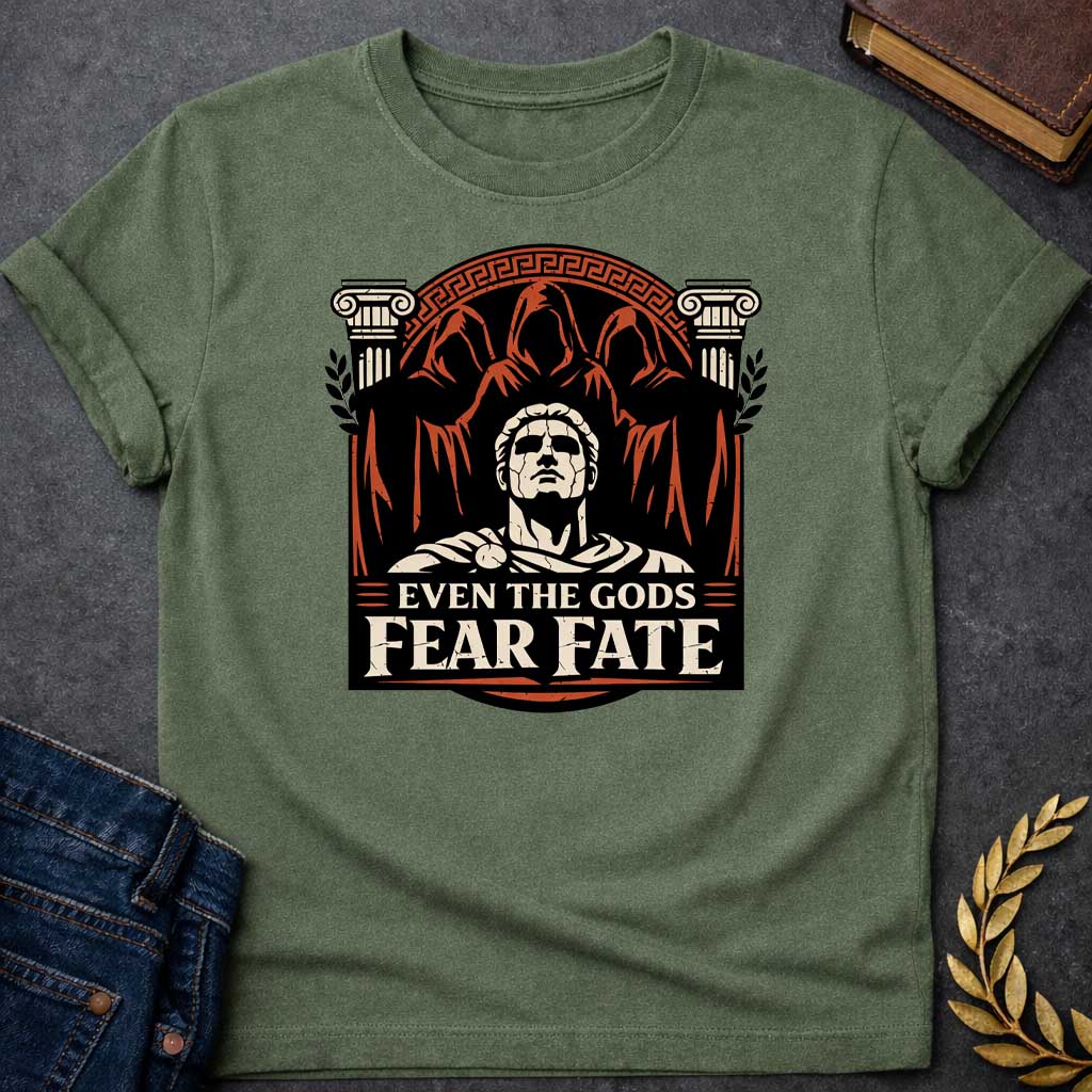Military Green shirt featuring a striking graphic design with a classical Greek aesthetic. In the center, a cracked marble bust of a Roman figure gazes upward, flanked by two Ionic columns. Looming behind the statue are three shadowy, hooded figures representing the Fates. The scene is enclosed in a circular Greek key border. The color palette is a bold trio of cream, burnt orange, and black. Below the art, the text reads "EVEN THE GODS" in a clean serif font and "FEAR FATE" in large, distressed block lette