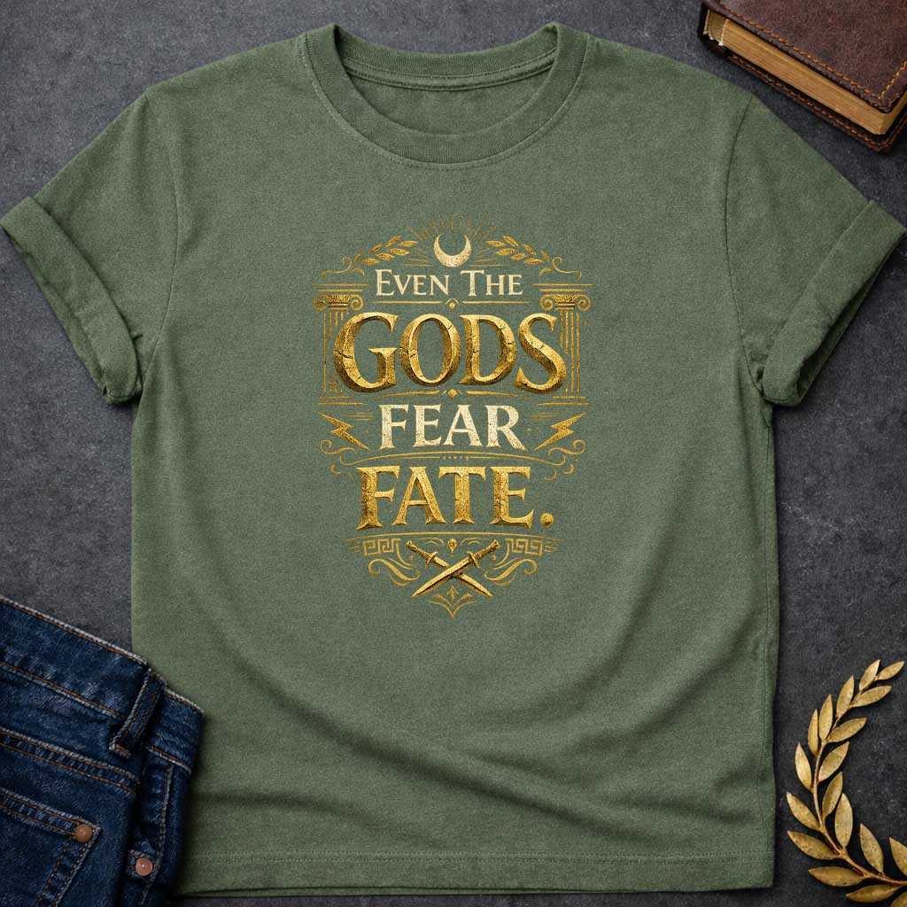 Military Green t-shirt featuring a high-contrast, mythic gold design. The text reads 'EVEN THE GODS FEAR FATE.' in distressed, 3D chiseled gold letters. The typography is framed by Greek architectural elements: an Ionic column on each side, a top crescent moon with laurel branches, jagged lightning bolts, and a bottom section with crossed ancient daggers above a Greek key pattern. The overall aesthetic resembles weathered, metallic ancient stone carvings, creating a vintage and powerful look.