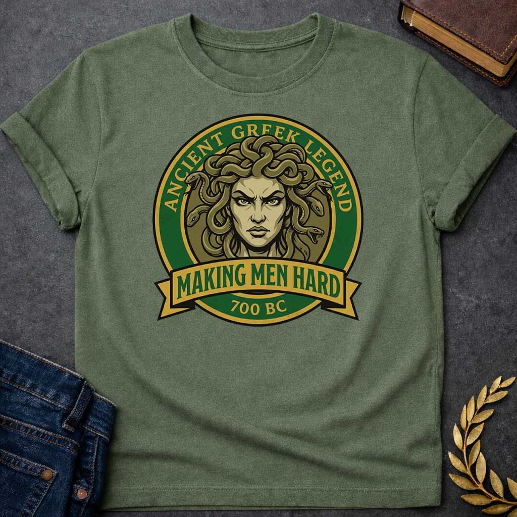 Military Green T-shirt graphic featuring a bold vintage badge design in forest green and gold. A fierce front-facing illustration of Medusa with coiling olive-toned snakes for hair and an intense glaring expression fills the circular center, with gold arched text reading "Ancient Greek Legend" around the upper border. A gold ribbon banner below the portrait reads "Making Men Hard" in green text, with "700 BC" below it — a witty double entendre referencing Medusa's mythological power to turn men to stone