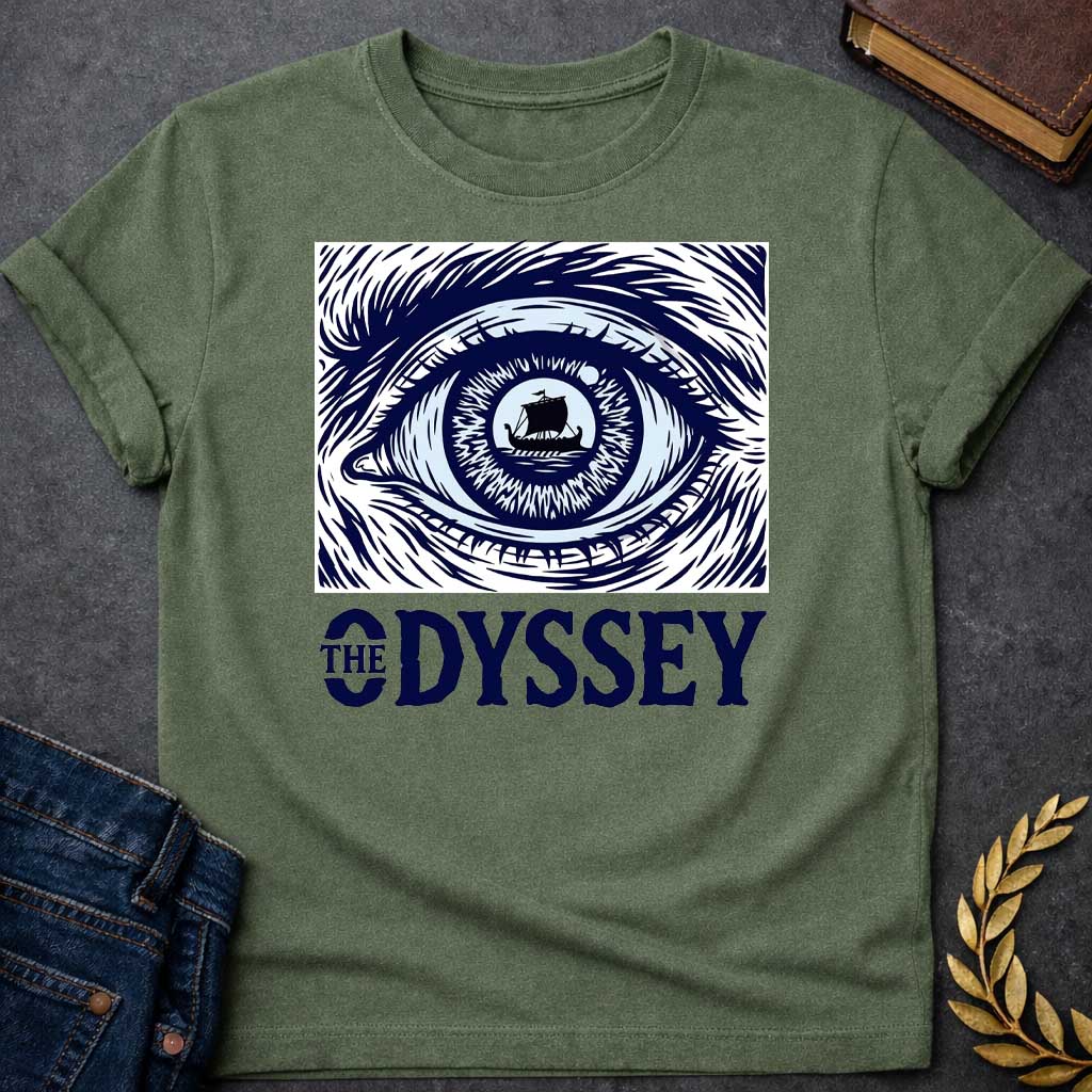 Military Green T-Shirt with a dramatic graphic design for 'The Odyssey' featuring a stylized eye in navy blue and white. The iris contains a silhouette of an ancient Greek ship with a single sail, surrounded by radiating lines suggesting both an iris pattern and oceanic waves. Swirling, turbulent linework evokes stormy seas and Odysseus's tumultuous journey. Bold serif text reads 'THE ODYSSEY' in navy blue. Combines classical maritime imagery with modern design, emphasizing vision, journey, destiny, and fat