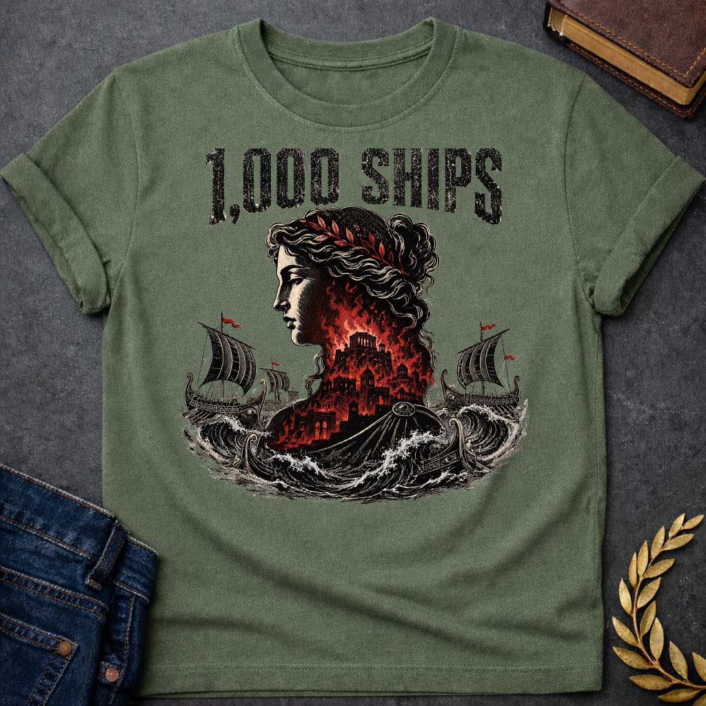 Military Green T-shirt with a dramatic illustration of Helen of Troy in profile with curly hair and red laurel crown. Her silhouette contains the burning city of Troy in red and black flames. Greek warships with red flags sail through turbulent waves on either side. Bold distressed text reads '1,000 SHIPS' above. References the famous phrase 'the face that launched a thousand ships' describing Helen's beauty that sparked the Trojan War.