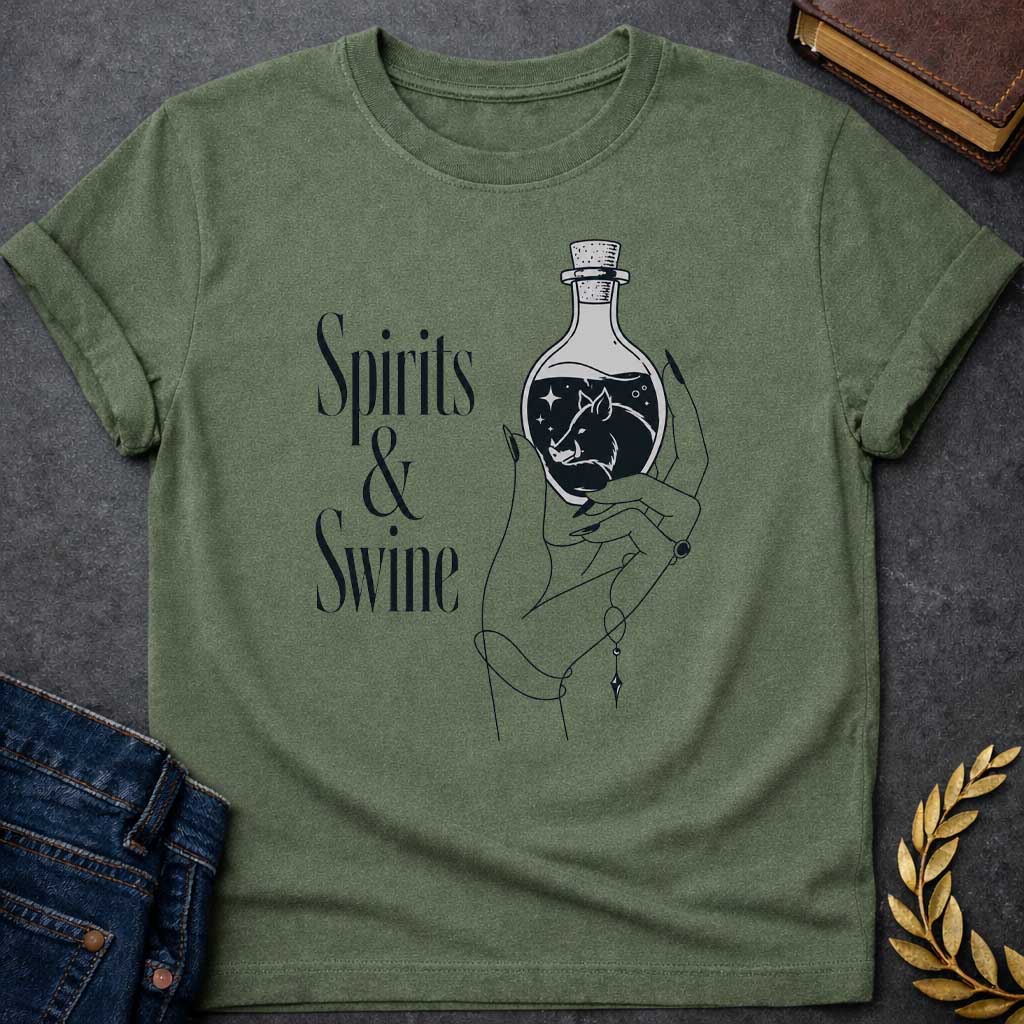 Military Green T-shirt with a Minimalist line art illustration of a mystical hand holding a potion bottle labeled 'Spirits & Swine.' Inside the dark bottle, a pig silhouette appears amid glowing stars and magical elements. The elegant hand wears decorative bracelets and rings. Black and white aesthetic with witchy, occult vibes. References Circe's legendary enchanted spirits that transformed men into swine. Celebrates ancient magic, potion-making, and mythological transformation with modern witchcraft theme