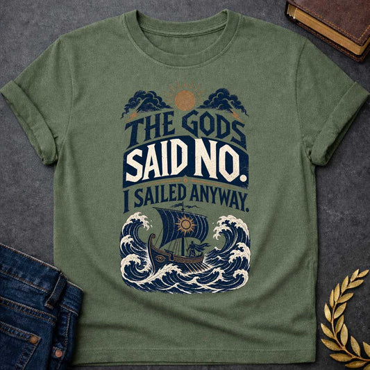 Military Green t-shirt with a Vintage Greek mythology design featuring the bold phrase “The Gods Said No. I Sailed Anyway.” An ancient Greek ship battles towering ocean waves beneath storm clouds, lightning bolts, and a glowing sun. Distressed navy, cream, and gold artwork captures the defiant spirit of Odysseus and The Odyssey.
