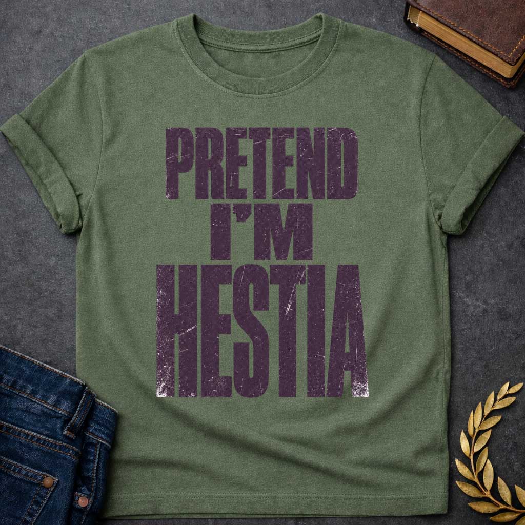 Military Green t-shirt with a Pretend I’m Hestia Greek mythology design featuring bold distressed dark purple typography on a transparent background. The stacked text reads “PRETEND I’M HESTIA” in a rugged vintage block font, creating a humorous design inspired by Hestia, the Greek goddess of the hearth, home, family, and domestic life.