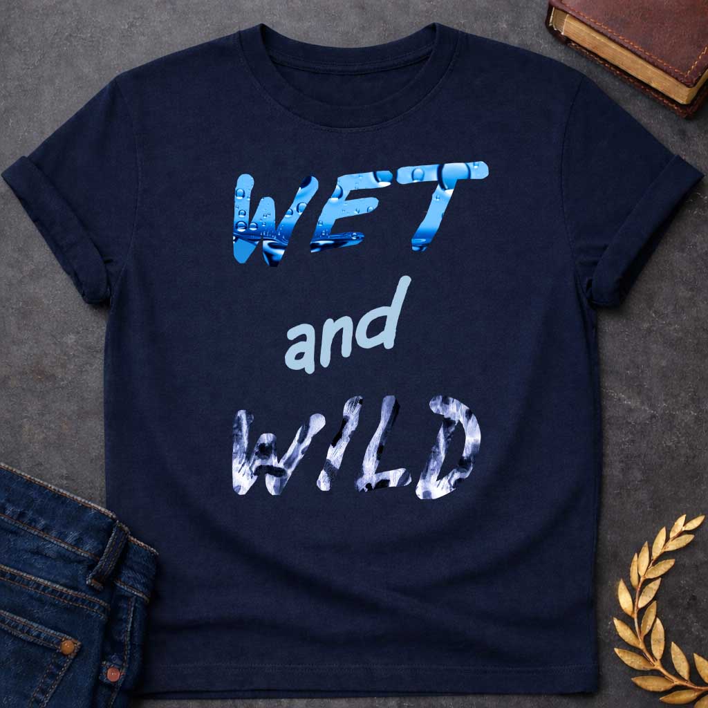 Navy T-Shirt with a graphic design featuring the phrase "WET and WILD" in three stacked rows. The word "WET" is at the top in a large, bold, sans-serif font. The letters are filled with a high-definition image of bright blue water and splashing droplets. The word "and" is in the center in a smaller, lowercase, light-blue cursive-style font. The word "WILD" is at the bottom in the same large, bold font as "WET," but the letters are filled with a black-and-white leopard or cheetah print pattern