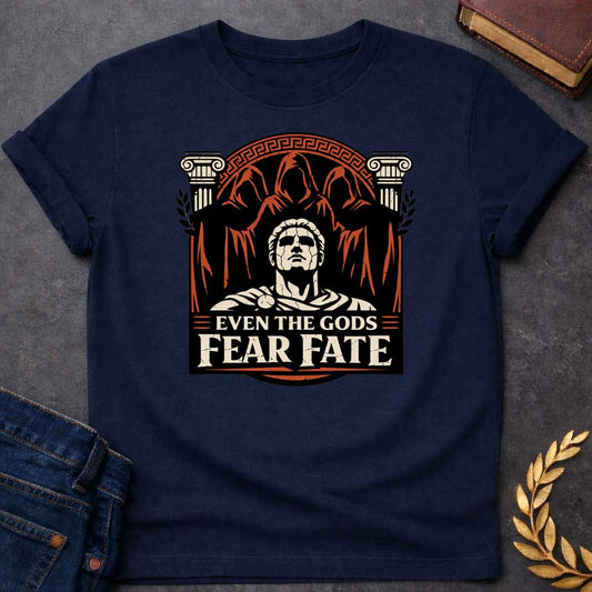 Navy shirt featuring a striking graphic design with a classical Greek aesthetic. In the center, a cracked marble bust of a Roman figure gazes upward, flanked by two Ionic columns. Looming behind the statue are three shadowy, hooded figures representing the Fates. The scene is enclosed in a circular Greek key border. The color palette is a bold trio of cream, burnt orange, and black. Below the art, the text reads "EVEN THE GODS" in a clean serif font and "FEAR FATE" in large, distressed block letters