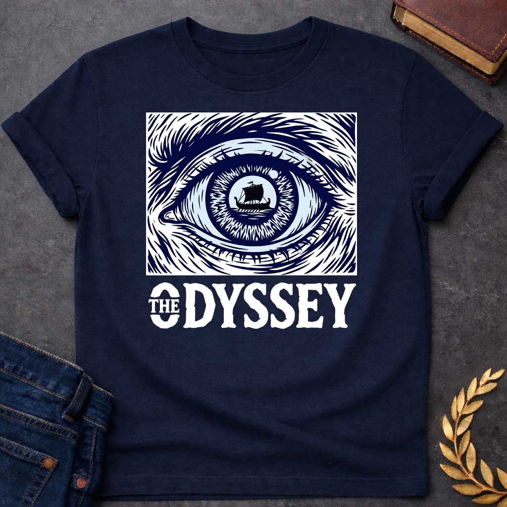Navy T-Shirt with a dramatic graphic design for 'The Odyssey' featuring a stylized eye in navy blue and white. The iris contains a silhouette of an ancient Greek ship with a single sail, surrounded by radiating lines suggesting both an iris pattern and oceanic waves. Swirling, turbulent linework evokes stormy seas and Odysseus's tumultuous journey. Bold serif text reads 'THE ODYSSEY' in white. Combines classical maritime imagery with modern design, emphasizing vision, journey, destiny, and fate.