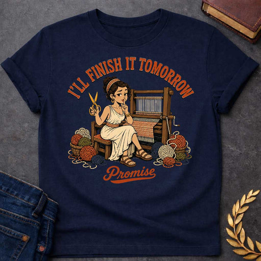 Navy T-Shirt with a humorous cartoon of Penelope at a wooden loom, holding scissors and making a 'shh' gesture. She wears a cream chiton with Greek key pattern belt, with curly brown hair. Baskets of colorful yarn surround her. Text reads 'I'LL FINISH IT TOMORROW' above and 'Promise' below. Comedic reference to Penelope's famous delaying tactic of weaving and unweaving her shroud to avoid suitors, reframed as modern procrastination humor.