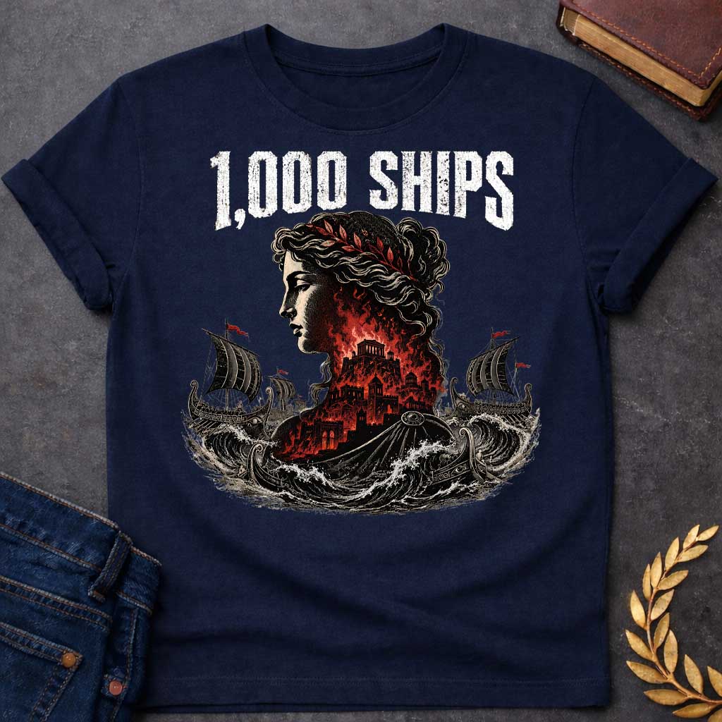 Navy T-shirt with a dramatic illustration of Helen of Troy in profile with curly hair and red laurel crown. Her silhouette contains the burning city of Troy in red and black flames. Greek warships with red flags sail through turbulent waves on either side. Bold distressed text reads '1,000 SHIPS' above. References the famous phrase 'the face that launched a thousand ships' describing Helen's beauty that sparked the Trojan War.