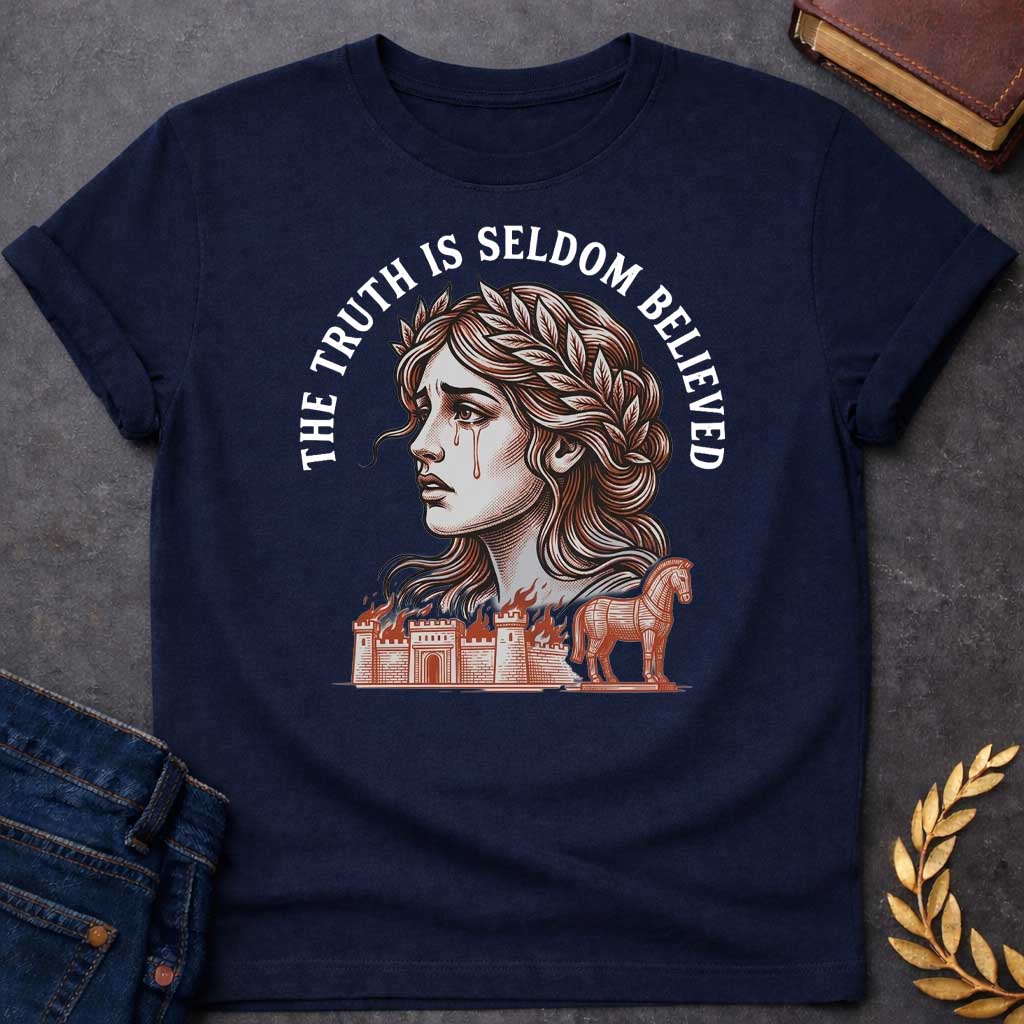 Navy T-shirt with a A Greek mythology design featuring a detailed woodblock-engraving style illustration of a crying Cassandra in profile. She wears a laurel wreath, with tears streaming down her face. Arched above her is the text "THE TRUTH IS SELDOM BELIEVED" in a bold white serif font. Below her portrait, a burning ancient city wall and the Trojan Horse are illustrated in a fine-line, terracotta-orange style.