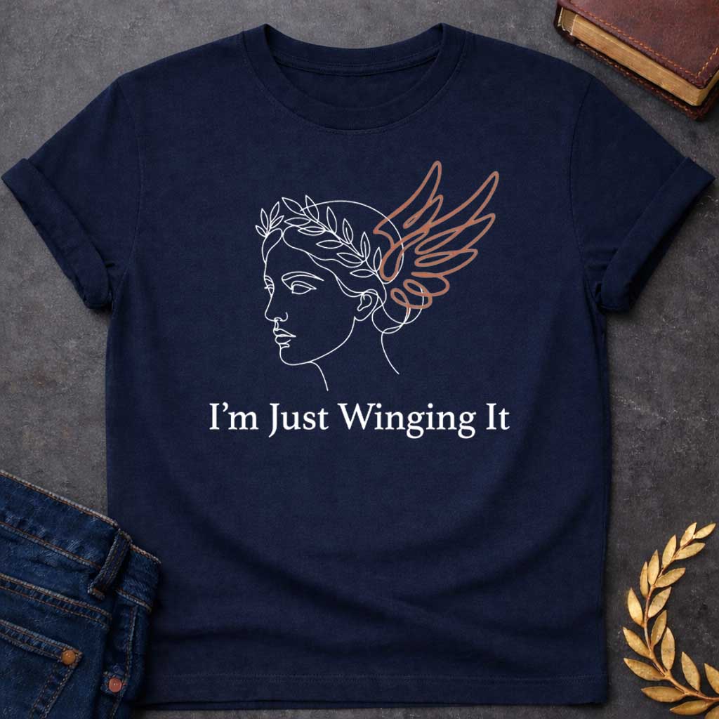 Navy T-shirt with a Minimalist line art illustration of a classical Greek profile with a laurel wreath crown and large terracotta-colored wings extending from the head. Elegant continuous line drawing style. Text reads 'I'm Just Winging It' in serif font below. References Nike, the goddess of victory, with a humorous modern spin. Blends classical mythology with relatable contemporary humor about improvisation and navigating life without a plan.