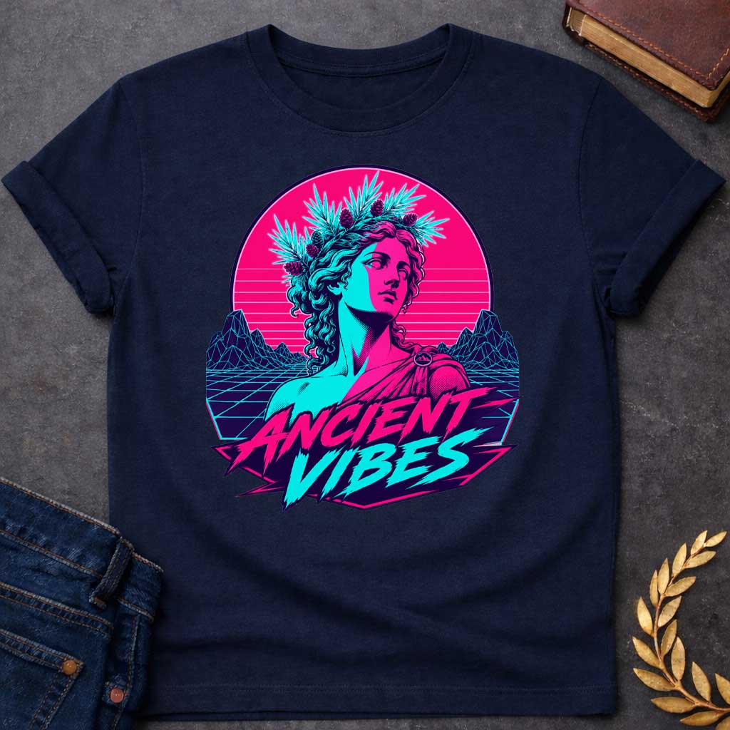 Navy T-shirt with a Vaporwave-style illustration of a classical Greek Nymph bust in neon magenta and cyan. The figure wears a laurel wreath crown and draped robes with split-color digital aesthetic. Geometric mountains and grid pattern landscape create a retro 80s vibe. Horizontal scan lines suggest digital distortion. Bold text reads 'ANCIENT VIBES' in magenta and cyan with star accents. Navy blue border frames the design. Blends classical Greek aesthetics with modern synthwave style.